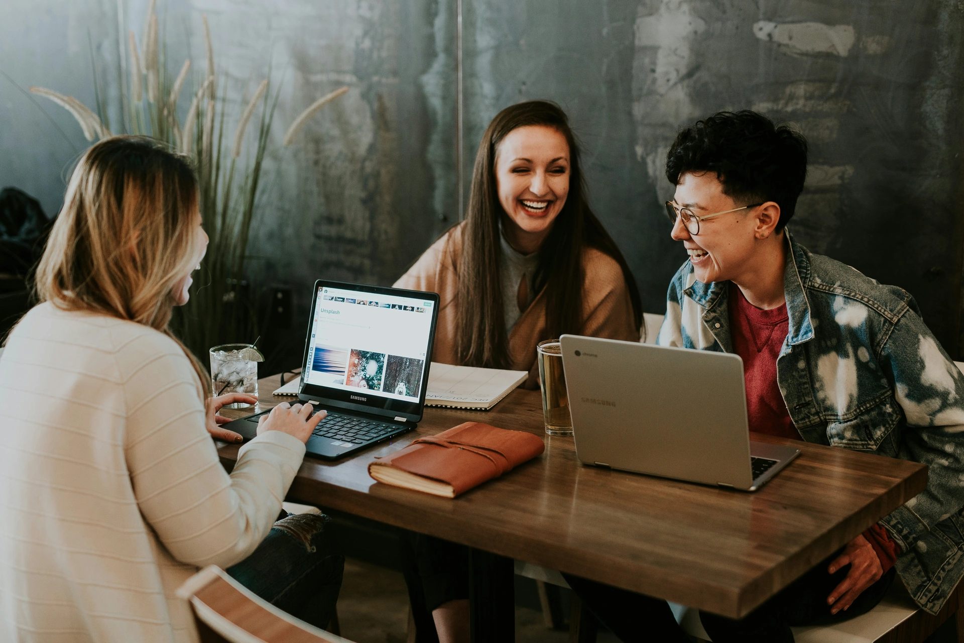 Tres personas comparten ideas alrededor de una mesa con portátiles